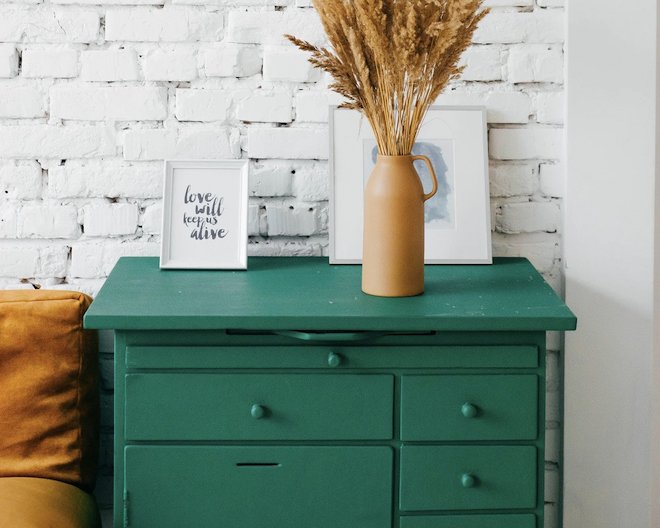 drawers with a vase and pictures on top of it